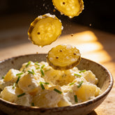 ACIDE Bread & Butter Zucchini Pickles coins mid-fall into a bowl of fresh potato salad
