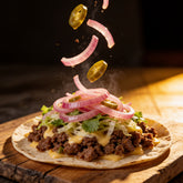 ACIDE Jalapeno Onions and jalapeno slices caught mid-fall onto a loaded beef taco