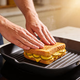 Hands pressing a grilled cheese and pickle toastie with ACIDE Bread and Butter Zucchini Pickles