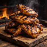 Grilled chicken wings glazed and glistening on a wooden board with char marks