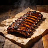 Rack of pork ribs with a glossy dark glaze resting on butcher paper