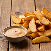 Pile of golden hot chips with a bowl of pale-brown dipping sauce