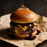 Beef brisket burger patty with a dark glossy sauce glaze and melted cheese on a toasted bun