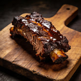 Close-up of beef short ribs with a dark glossy lacquered glaze on a wooden board