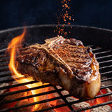 Jimmy Brisket Special Ops 280g beef rub — peppery seasoning falling onto a T-bone steak searing over hot coals