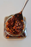 Ma Foo Chilli Oil jar with a spoon lifting crispy chilli and shallot solids from the oil