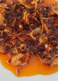 Close-up of Nonna Piccante Chilli Oil showing chilli flake, capers and porcini in olive oil
