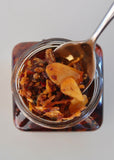 Nonna Piccante Chilli Oil jar with a spoon lifting crispy chilli, shallot and porcini from the oil