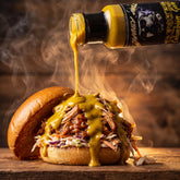 Capones Columbian Gold mustard sauce poured onto an open pulled pork burger