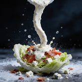 Atomic Chicken Blue Cheese Sauce 250ml — dressing drizzled over a wedge salad, frozen mid-pour
