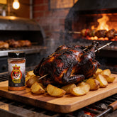 Atomic Chicken Charcoal Chicken Seasoning Rub 280g — whole charcoal-roasted rotisserie chicken on a board with roast potatoes beside the shaker