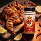 Atomic Chicken Chicken Peri Peri Seasoning Rub 200g — butterflied flame-grilled peri peri chicken with lemon and chilli beside the shaker