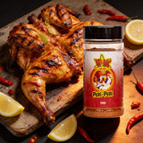Atomic Chicken Chicken Peri Peri Seasoning Rub 200g — butterflied flame-grilled peri peri chicken with lemon and chilli beside the shaker