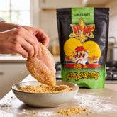Atomic Chicken Chicken Schnitzel Herb & Garlic Coating 450g — hands crumbing a raw schnitzel at the kitchen bench