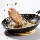 Atomic Chicken Chicken Schnitzel Original Coating 450g — crumbed schnitzel frozen mid-drop into a hot frying pan