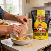 Atomic Chicken Chicken Schnitzel Original Coating 450g — hands crumbing a raw schnitzel at the kitchen bench