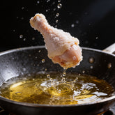 Atomic Chicken Gluten Friendly Original Southern Fried Chicken Coating 500g — coated drumstick dropping into hot oil, frozen mid-splash