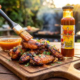 Atomic Chicken Honey Mango BBQ Sauce — sticky honey-mango glazed BBQ wings being brushed with the sauce on a board