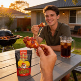 Atomic Chicken Hot 'N Spicy Southern Fried Chicken Coating 500g — man enjoying a glazed drumstick at a backyard BBQ at sunset