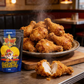 Atomic Chicken Original Southern Fried Chicken Coating 500g — steaming pile of crispy fried drumsticks beside the pack, juicy bitten piece showing