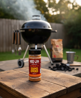 BBQ Lab Island Smoke rub jar on a bench beside a kettle BBQ