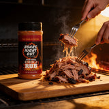 Two hands pulling apart smoked pork with forks, seasoned with Boars Night Out BBQ Rub