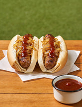Aussie snags in bread with fried onions and Booma's BBQ Boomtang BBQ sauce