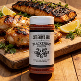 Cattleman's Grill Blackening Seasoning 281g steak rub — beauty shot, blackened fish glistening with the seasoning crust, plated with lemon and thyme