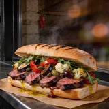 Chuck Hughes Mild Antipasto 375ml antipasto condiment — chargrilled steak sandwich heaped with antipasto on a laneway bench at night