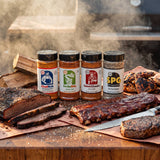 Chuds BBQ Range Bundle Texas rubs and seasonings — all four shakers with a full barbecue spread on a timber block