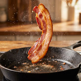 Coast n Smoke Bacon Cure — a rasher of homemade bacon lifted sizzling from the pan with a crisp curl