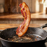 Coast n Smoke Bacon Cure — a rasher of homemade bacon lifted sizzling from the pan with a crisp curl