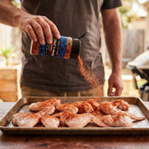 Coast n Smoke K-Pop Dust Korean BBQ — cook dusting raw chicken wings with the vivid red Korean seasoning