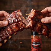 Coast n Smoke The Rip rub — smoked pork ribs pulled apart showing tender juicy meat and glossy bark