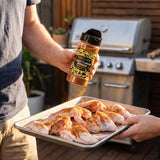Coast n Smoke Winki-POP Dust — cook dusting raw chicken wings heavily with the seasoning on a tray