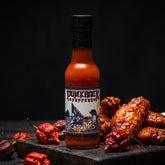 Punk Rock Peppers Casualties Carolina Reaper hot sauce styled with wings and chillies