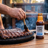 Hardcore Carnivore Saucesome BBQ Sauce — basting ribs on the grill with the sauce