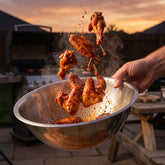 Heavenly Hell Cluckin Hell hot chicken rub 150g — spicy chicken wings tossed mid-air in a steel bowl with rub in the air
