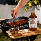 Basting smoked pork ribs on a kettle grill with Lillie's Q Smoky Barbeque Sauce