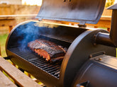 Low & Slow Brisket Box lifestyle — whole brisket smoking on an offset smoker with visible bark and smoke