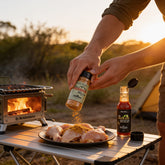 McAdventures The Expedition Pack being used at an outdoor camp table, seasoning chicken with both products, in-use lifestyle