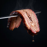 Middle Kingdom Beef Berserker 170g steak and brisket seasoning — a brisket slice draping over a knife with a pink smoke ring and beading juice