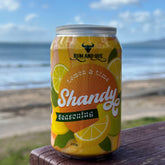 Rum and Que Shandy lemon-lime beer rub can on a beachside table