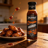 TAIPAN BBQ Habanero medium smoky-sweet BBQ sauce 250ml — action shot, sauce drizzling over wings mid-air