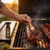 TAIPAN BBQ Smoky Glaze mild smoky BBQ glaze 250ml — in-use shot, brushing glaze onto ribs on the smoker