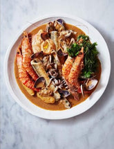 The Whole Fish Cookbook by Josh Niland hardback cookbook — interior page of a seafood stew with prepared fish and shellfish