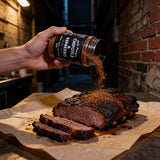 Uncle Mungo's Chipotle & Espresso 300g chipotle espresso dry rub — shaking chipotle and espresso rub over a smoked brisket