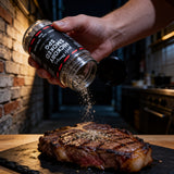 Uncle Mungo's Hickory Smoked SPG 300g hickory smoked salt pepper garlic rub — shaking hickory smoked SPG rub over a seared steak