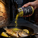 Uncle Mungo's Lemon & Herb 300g lemon and herb seasoning — shaking lemon and herb seasoning over crispy-skinned barramundi