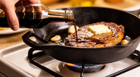 Worcestershire sauce poured into a cast iron pan with a seared steak, butter and garlic